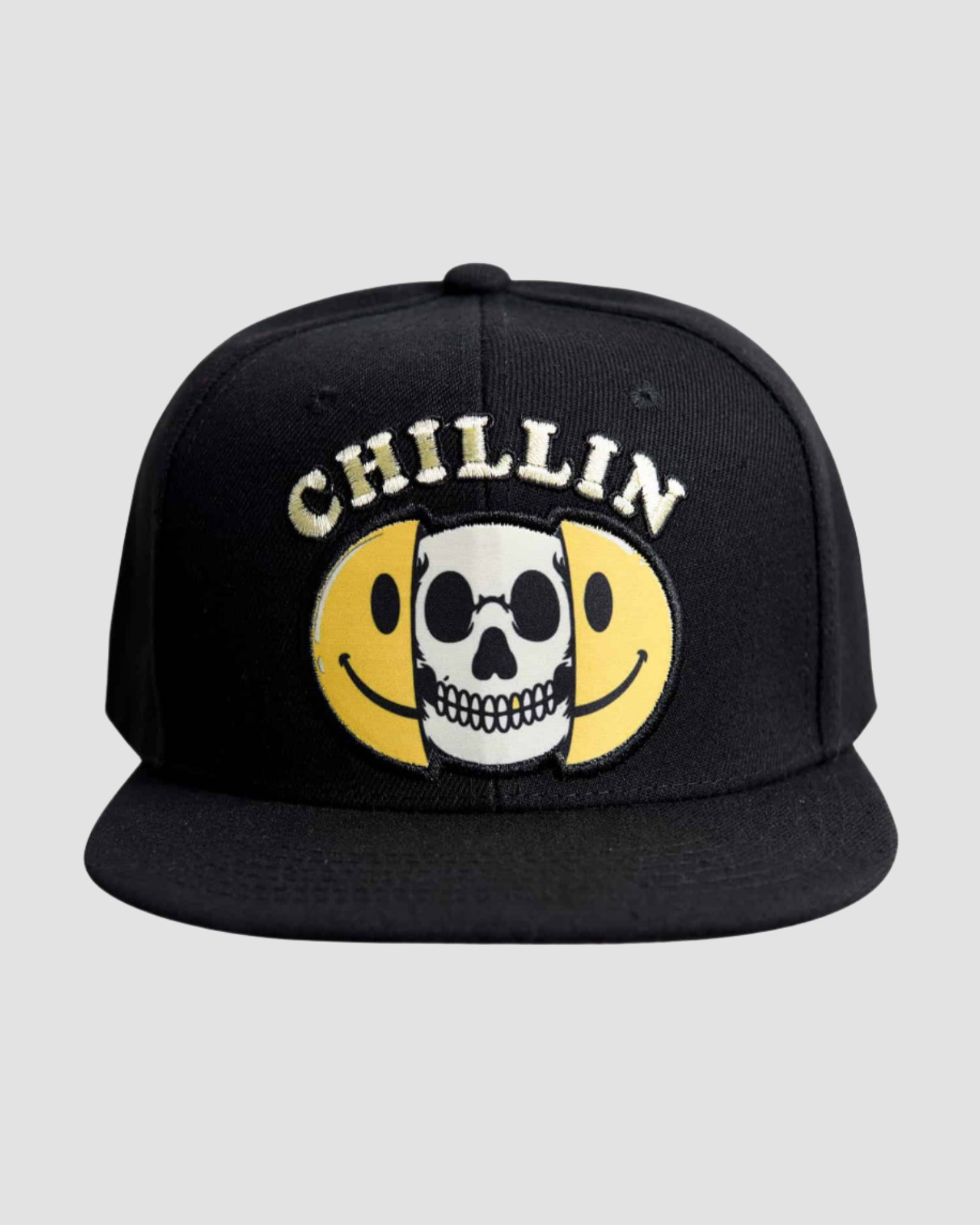 Front view of the ‘Men’s Chillin Snapback’ by Ring of Fire Clothing in Black, White, and Yellow color, showcasing the unique split happy face and skull design with ‘chillin’ text.