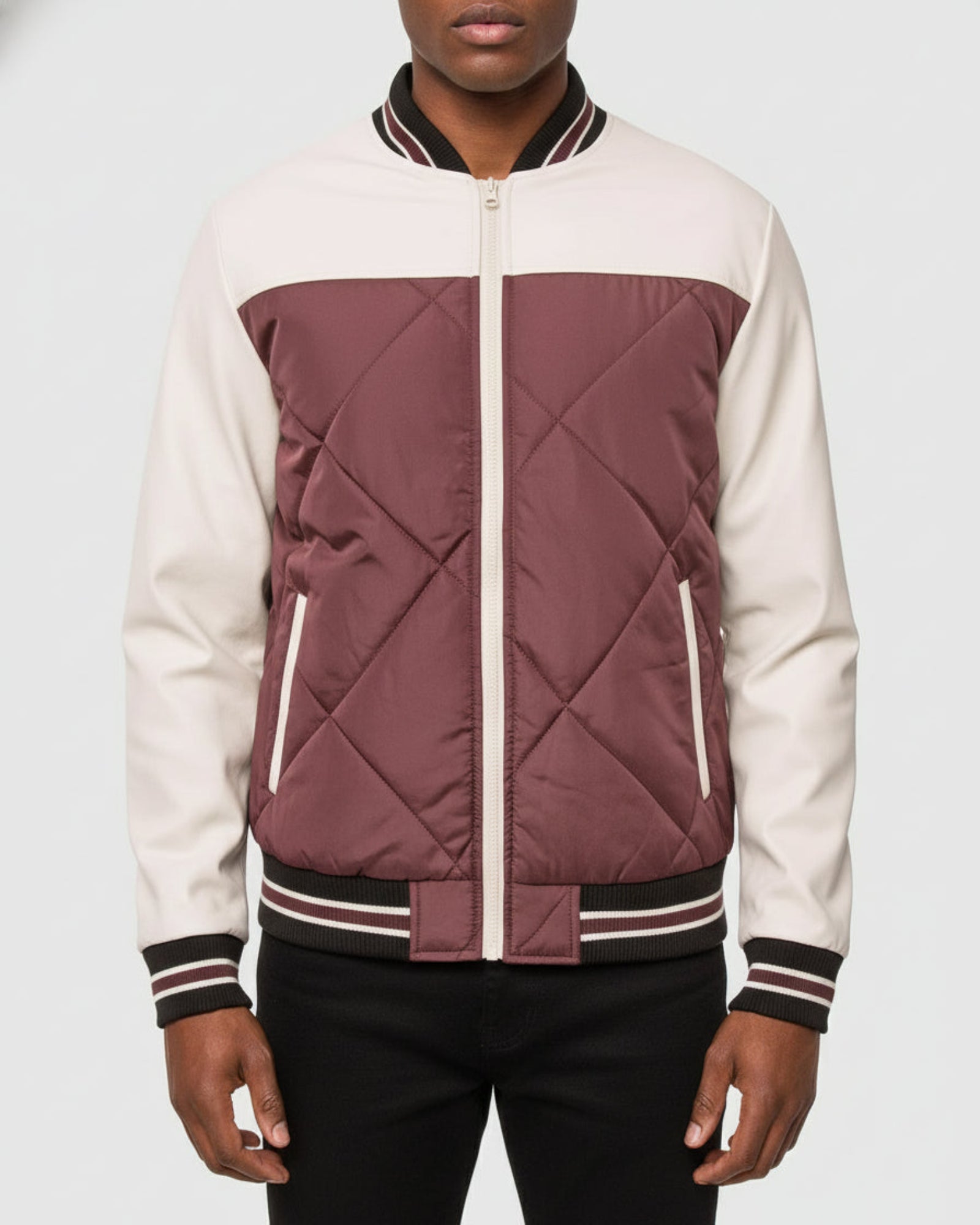 Person wearing a maroon and beige quilted jacket on a white background