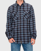 Person wearing a black and blue plaid shirt on a gray background
