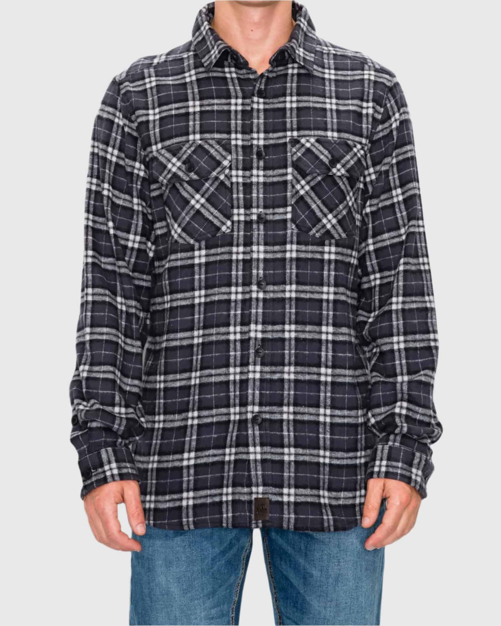 Person wearing a black and white plaid shirt with rolled-up sleeves on a gray background