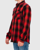 Red and black plaid shirt worn by a person on a gray background