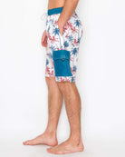 Side view of model wearing men’s boardshorts, highlighting the spacious cargo pocket and palm tree print.