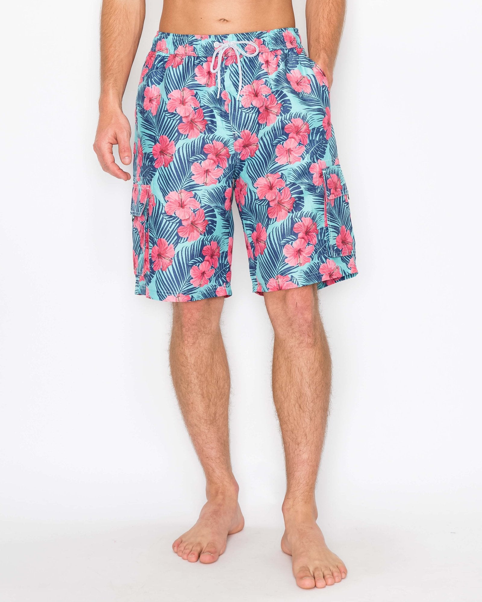 Model wearing Men’s Paradise Bloom Cargo Boardshorts, front view, featuring pink tropical flowers on a blue background, below-the-knee length.