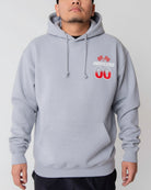 Person wearing a gray hoodie with a logo on the chest against a plain background
