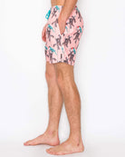 Person wearing pink swim shorts with a palm tree pattern on a white background